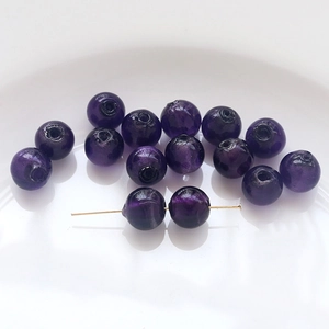Macro detail of deep purple crystal glass round beads with a gold needle showing hole size