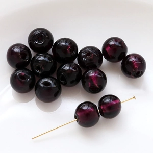 Macro shot of dark purple glass beads with gold foil texture for DIY jewelry making