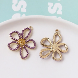 Détail macro d'un pendentif fleur en alliage avec perles mauves et dos en métal doré