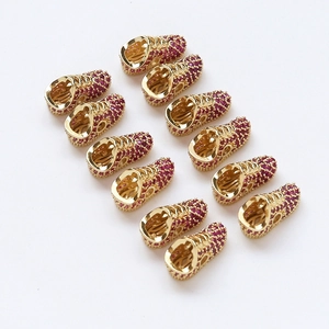 Macro shot of 12 gold-plated sneaker charms with red zircon pavé for DIY jewelry making