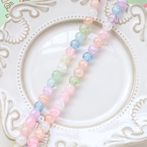 Close-up of macaron-colored glass beads with crackle texture in a white ceramic dish