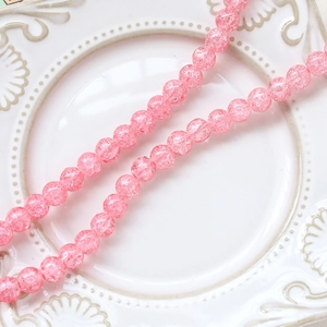 Macro shot of pink crackle glass beads on white porcelain plate for DIY jewelry making