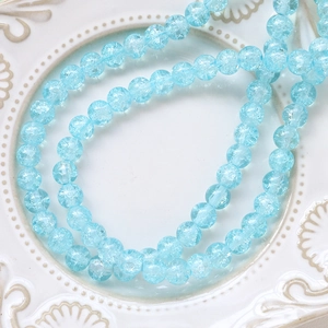 Macro detail of light blue cracked glass beads with ice textures on white ceramic plate