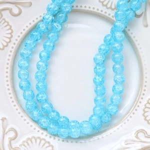 Macro shot of sky blue crackle glass beads on a vintage ceramic plate for DIY jewelry