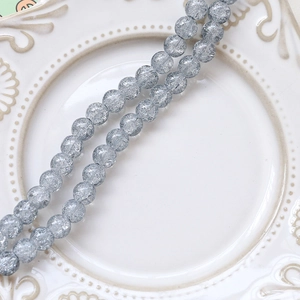 Macro shot of 6-8mm grey-blue crackle glass beads on white vintage porcelain plate