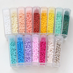 Macro view of 16 macaron colored glass seed beads in transparent plastic DIY storage boxes