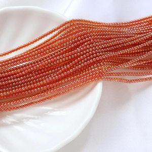 Détail macro de perles de rocaille 2mm rouge-orange irisées avec finition AB