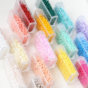 Macro shot of 3mm macaron colored glass seed beads organized in clear plastic storage boxes