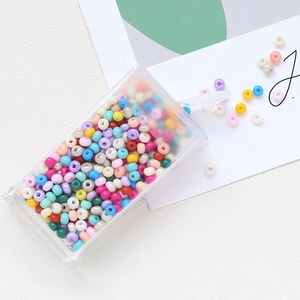 Macro shot of 3mm colorful macaron glass beads pouring from a transparent storage box