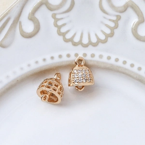 Macro shot of gold-plated bell-shaped pendants with zircons and hollow design for DIY jewelry