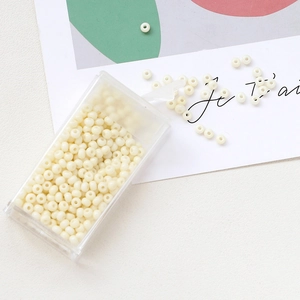 Macro detail of cream macaron seed beads in a clear storage box for DIY jewelry making