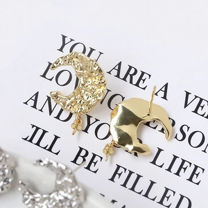 Macro detail of moon-shaped 925 silver stud earrings with hammered gold and silver texture