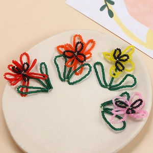 Detailed view of handmade beaded flower charms in red, orange, yellow and pink hues