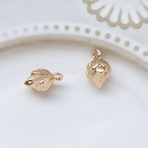 Macro view of gold-plated vintage hollow pinecone charms on white ceramic plate
