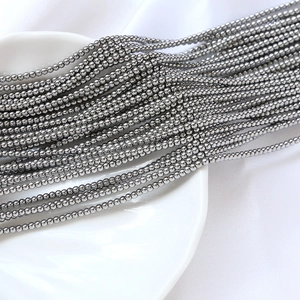 Vue macro de perles de rocaille de 2mm gris métallisé sur une assiette blanche