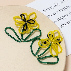 Macro view of handmade bead-woven yellow flower earring accessory on a beige stand