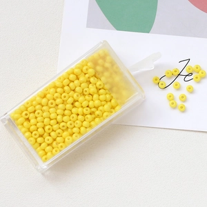 Macro detail of yellow macaron seed beads in a transparent plastic storage container