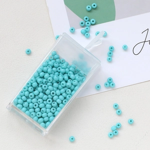 Macro detail of light blue 3mm glass beads in a clear plastic storage box for DIY jewelry