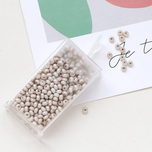 Detailed macro of cream macaron glass seed beads in a transparent rectangular plastic box