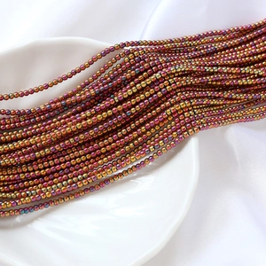 Vue macro de perles de verre irisées 2mm dorées et violettes pour création de bijoux DIY