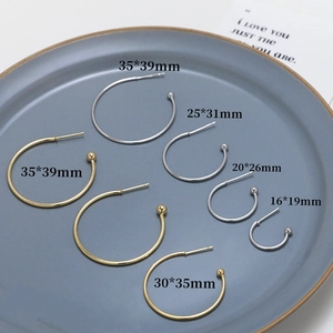 Various sizes of gold and silver C-shaped metal earring hooks displayed on a blue tray