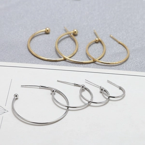 Detail of C-shaped gold and silver hoop earrings in four sizes with smooth metal finish