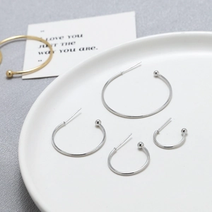 Detail view of minimalist silver C-shaped hoop earrings in four tiered sizes for women