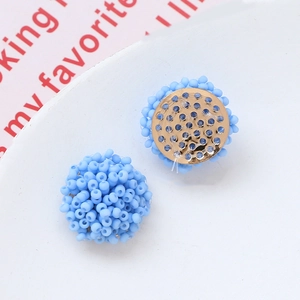 Vista detallada de pendientes de flores con cuentas azul macarrón y base dorada