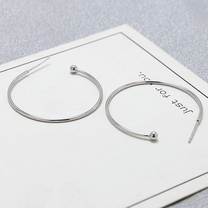 Detail view of silver S925 C-shape hoop earrings with metal beads on a display card