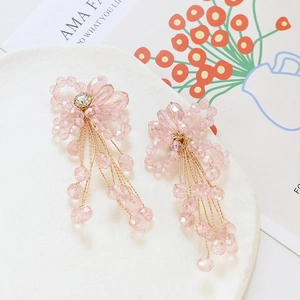 Detail of handmade pink crystal flower earrings with beaded tassels and gold metal wiring