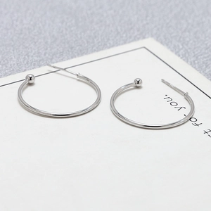 Macro detail of S925 sterling silver stamp on minimalist C-shaped hoop earrings