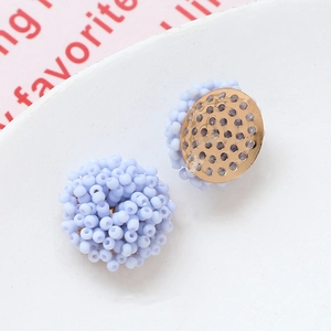 Detalle macro de pendientes de cuentas esmeriladas azul claro con base dorada