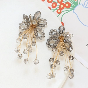 Detail of handcrafted flower bead earrings with gray crystals and gold wire tassels