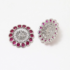 Detailed view of flower-shaped stud earrings with red zircons and silver base