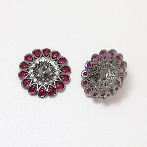 Macro detail of gunmetal floral studs with pink teardrop stones and white zircon accents