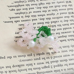 Dettaglio di pendente floreale fatto a mano con perle rosa, verdi e cristalli