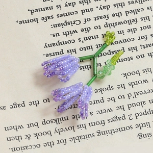Macro di un ciondolo floreale viola fatto a mano con accenti di perline di vetro verdi