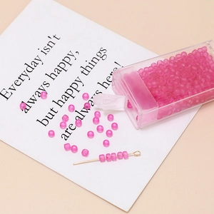 Macro detail of 3mm frosted peach pink seed beads with a storage box and golden eye pin