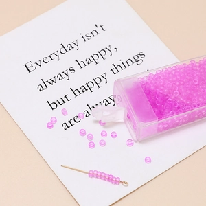 Detailed macro view of 3mm frosted pink-purple beads with threading needle and box