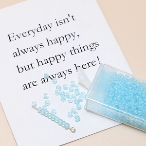 Detail of 3mm light blue translucent frosted glass seed beads in a clear box and on a card