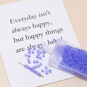 Detailed view of 3mm purple matte glass seed beads with a plastic storage organizer box