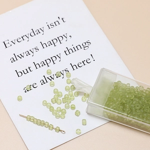 Macro shot of 3mm light green frosted glass seed beads in a plastic storage box for DIY