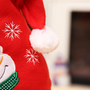 Detail of red felt Christmas hat with white snowflake embroidery and snowman patch