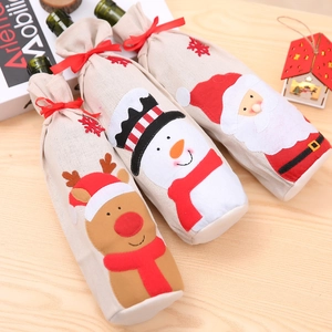 Detalle de fundas de arpillera para botellas de vino de Navidad con motivos de Papá Noel y renos