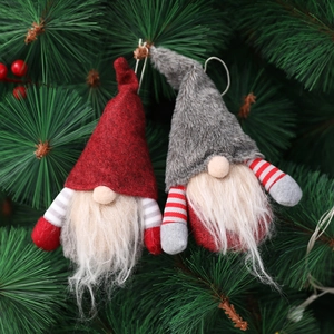 Handmade Christmas gnome hanging ornaments with red and grey hats on a green tree
