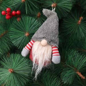 Plush Christmas gnome ornament with grey faux fur hat and white beard on a pine tree branch
