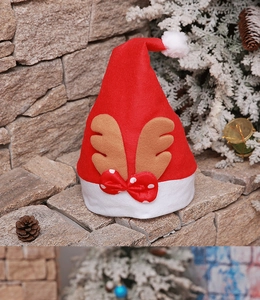 Detail of red felt Christmas reindeer hat with brown antlers and festive white pompom