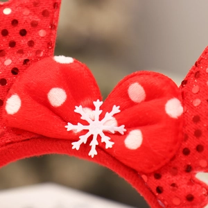 Macro shot of a red polka dot bow and snowflake detail on a sequined reindeer headband
