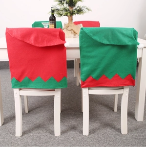 Festive red and green elf hat chair covers with pom-poms for Christmas dining decoration