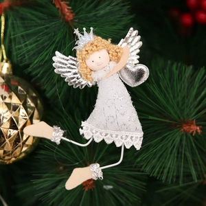 Detail of a white lace angel ornament with silver wings hanging on a green Christmas tree